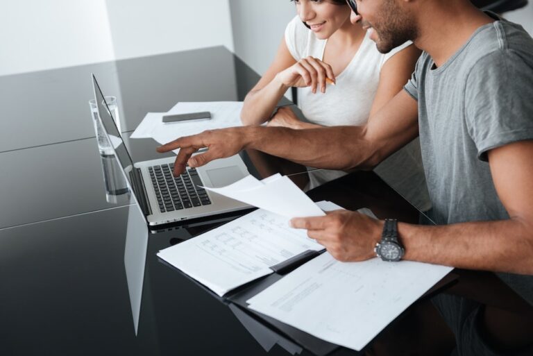 husband and wife looking over finances on paper and computer