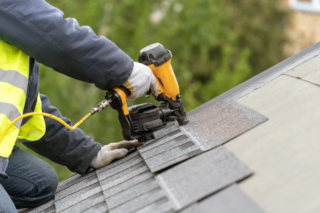 worker on the house roof installing shingles