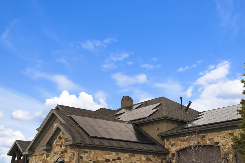 brown asphalt shingle roof on a stone home with solar panels