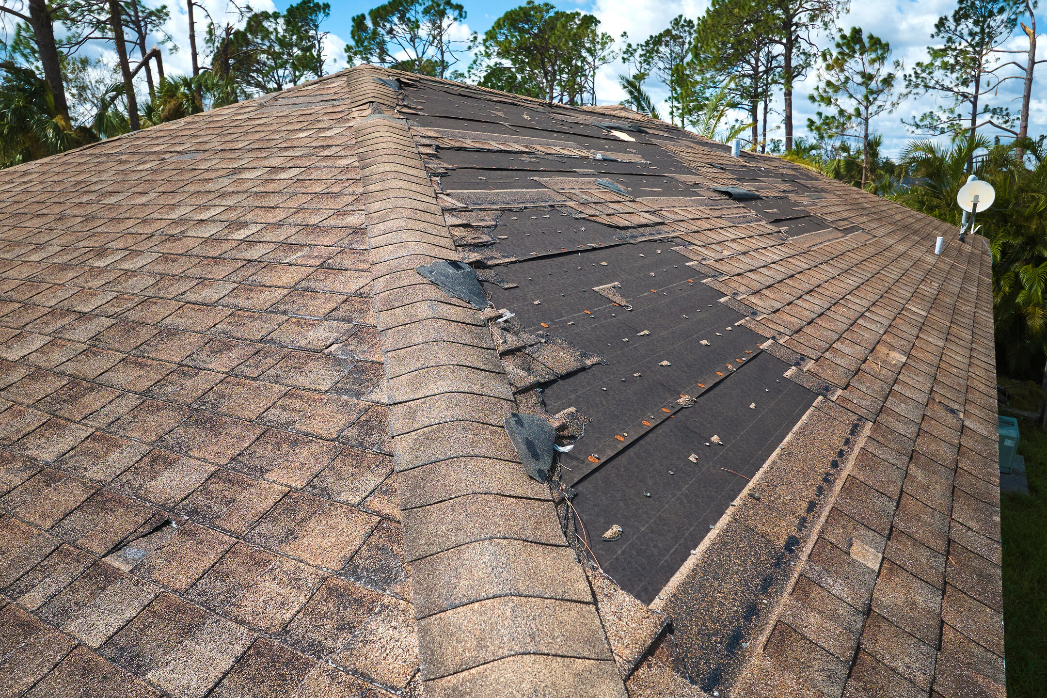 missing shingles-large patches of missing shingles of a brown roof