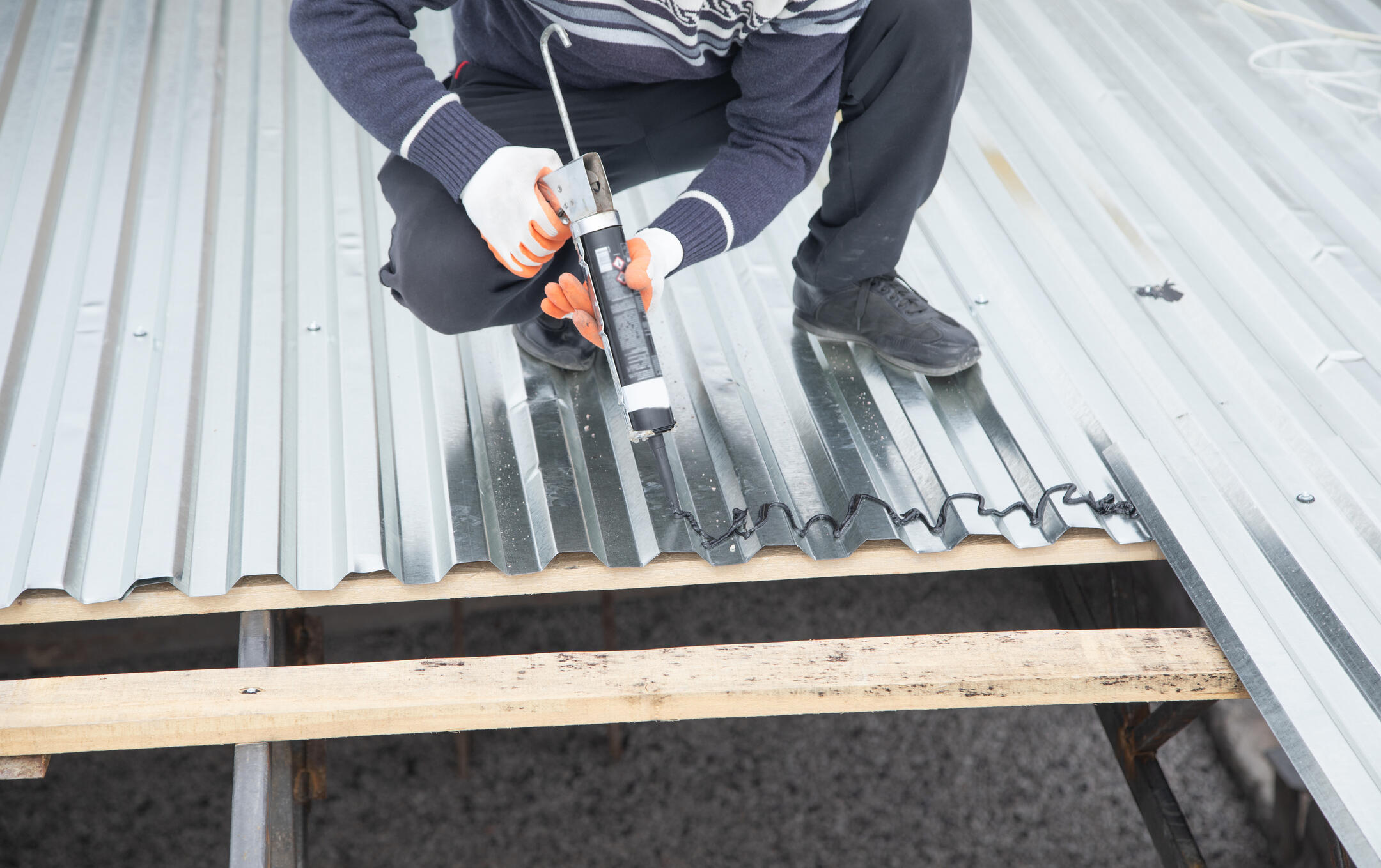 roof sealant-man applying a sealant to metal roofing materials