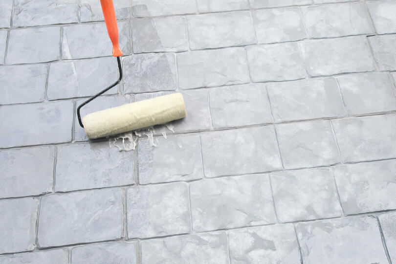 roof sealant-roller applying sealant to stone roofing materials