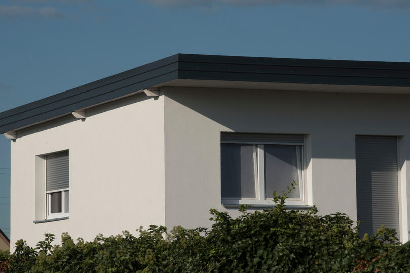 single ply membrane roof-white residential home with a flat roof surrounded by hedges