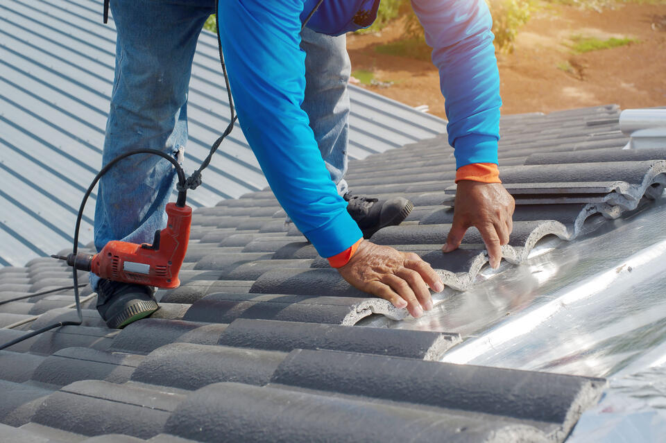 concrete tile roof-man installing slabs of concrete roof shingles