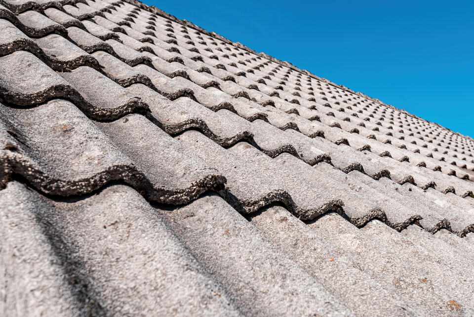 concrete tile roof-wavy concrete roof shingles on a sloped roof with blue sky background