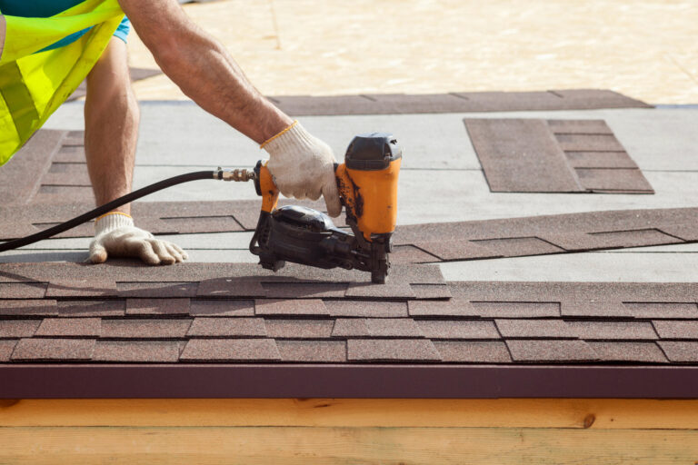 roofing tools-man wearing safety vest and gloves using power tool to install roof shingles